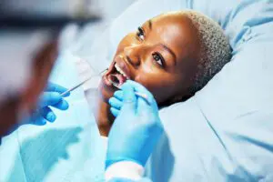 Woman in dental chair has teeth inspected by dentist