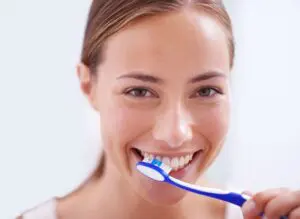 Woman with a toothbrush smiling and brushing her teeth