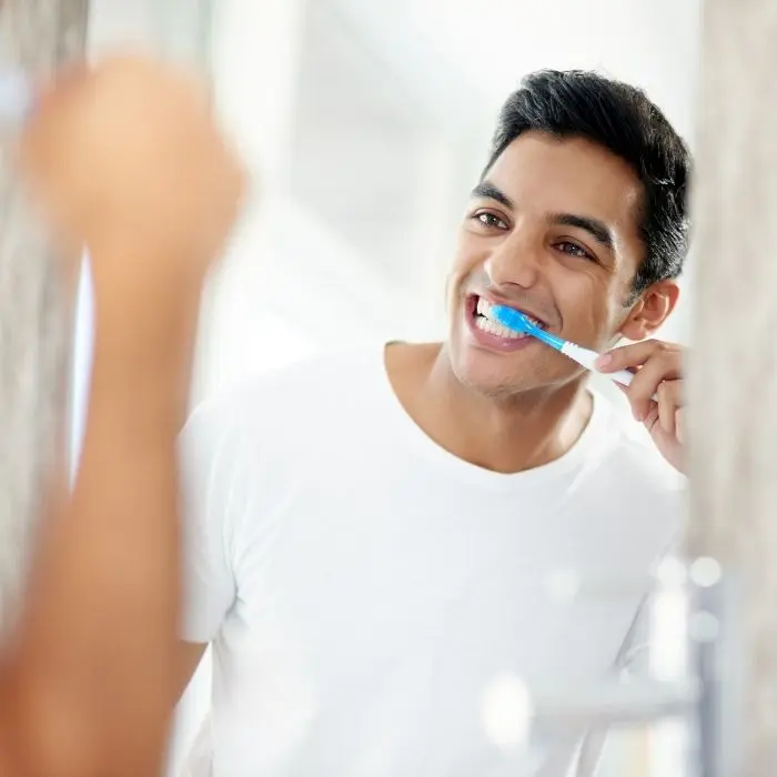 Man looking in the mirror while brushing his teeth