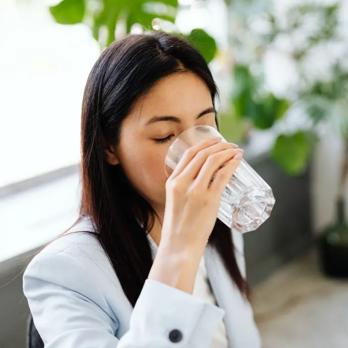 Woman drinking a glass of water to keep her teeth hydrated